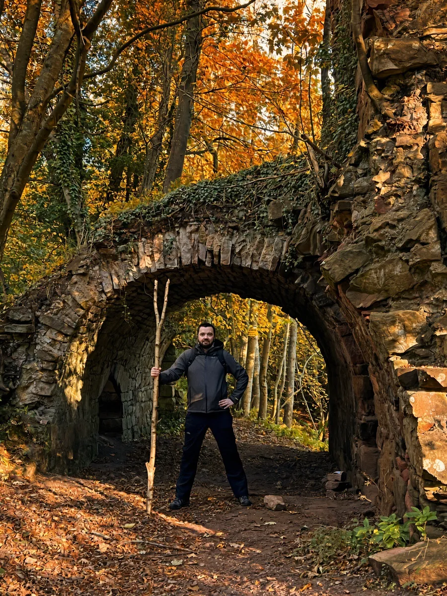 CastleScotland’s creator beneath a ruined stone arch in an autumn woodland